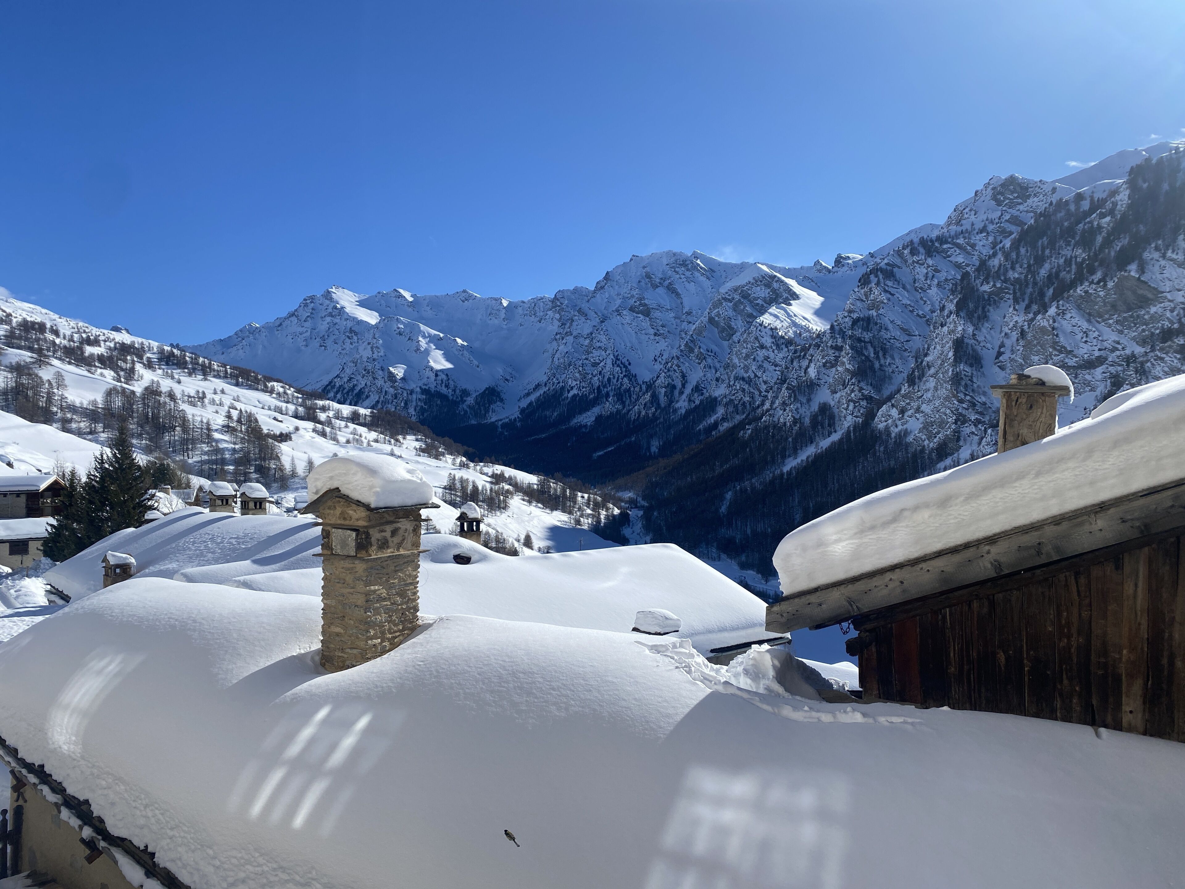 A snow-covered mountain village with traditional stone buildings and wooden structures.