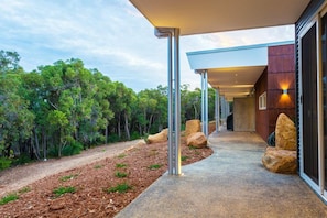 Walkway leads to a glass entrance surrounded by natural landscape and large rocks.