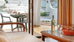 A dining area with a table, chairs, a bottle, and a basket of oranges. - Laguna Apartments (Mogan)