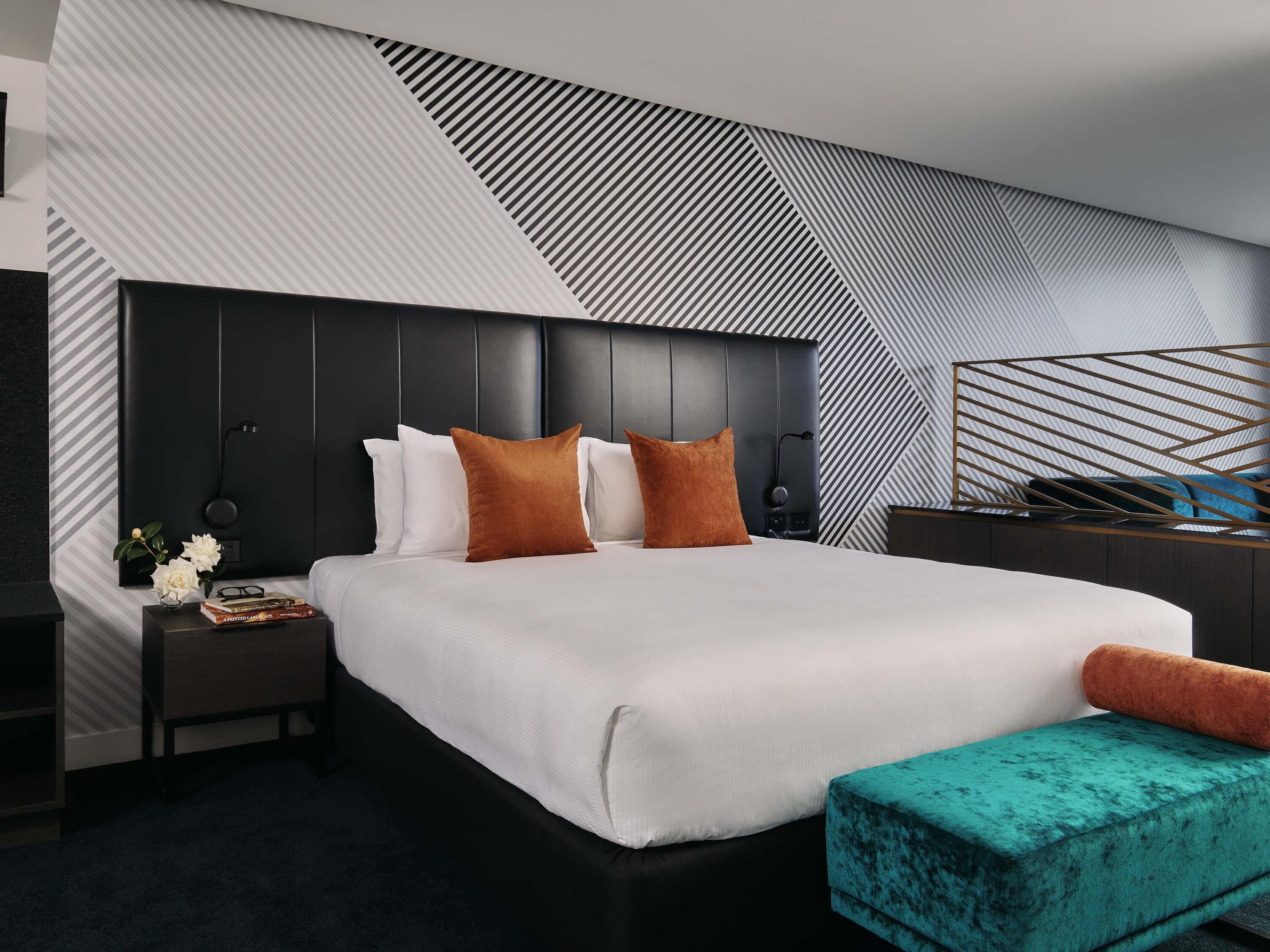 Una habitación de hotel moderna con una cama grande, una mesita de noche y un panel decorativo en la pared.