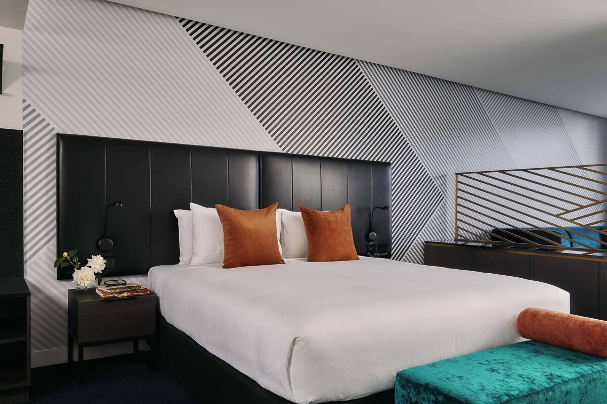 Una habitación de hotel moderna con una cama grande, una mesita de noche y un panel decorativo en la pared.