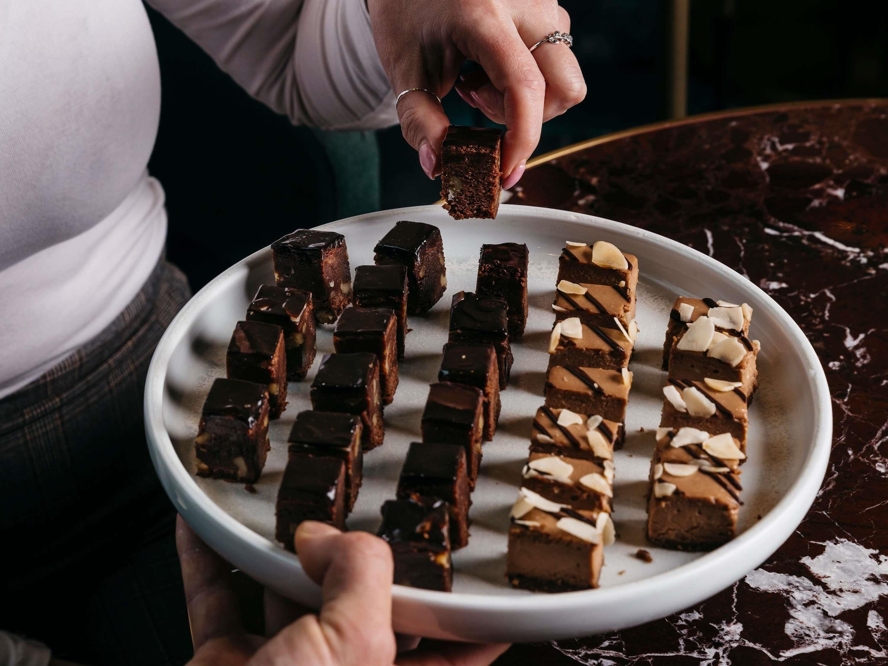 A person holding a plate with various chocolate bars.