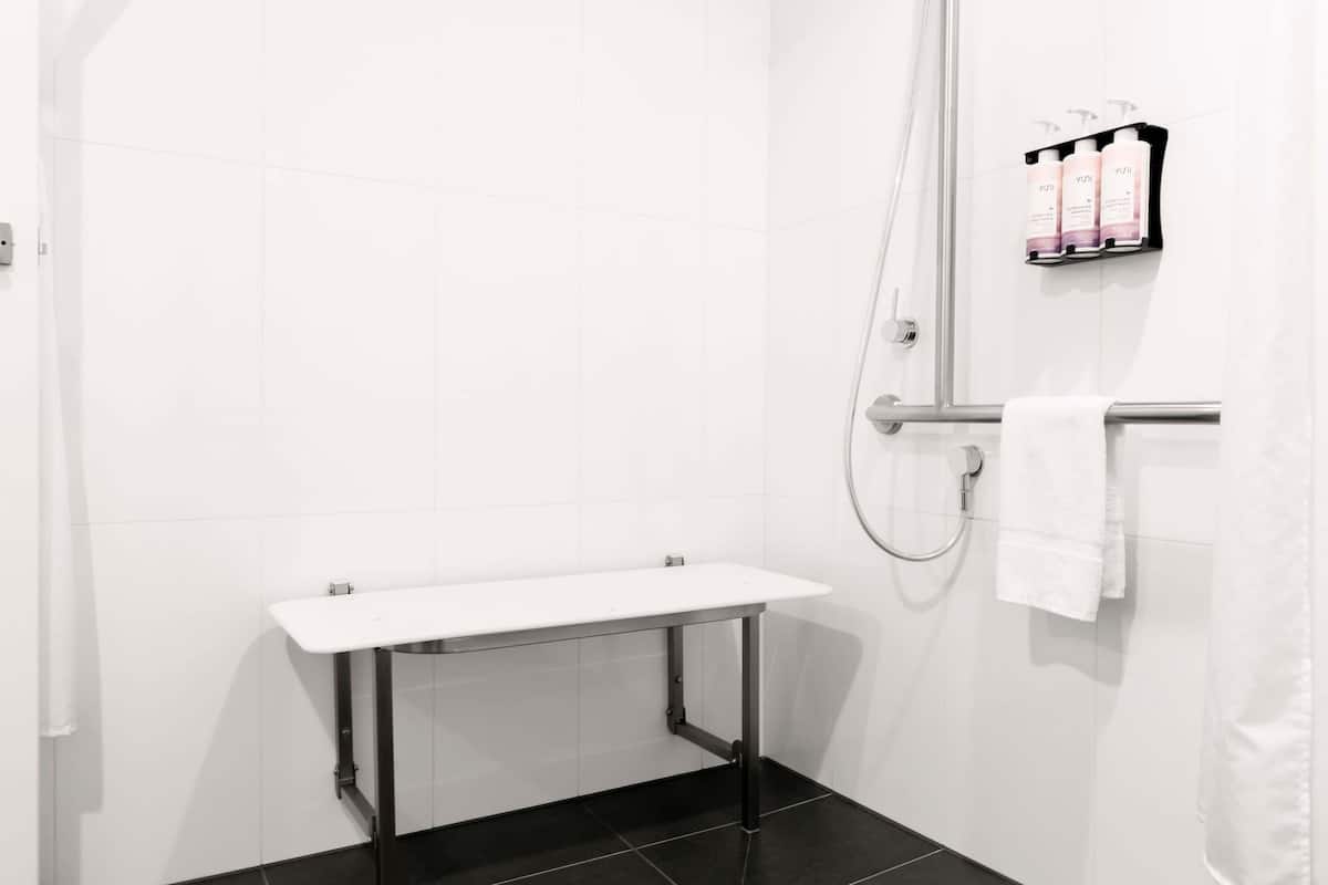Un baño moderno con ducha, un lavamanos blanco y un perchero para toallas.