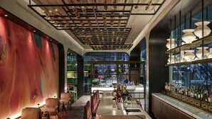 Zona de bar moderna con mostrador, asientos y vistas panorámicas de la ciudad a través de amplios ventanales.