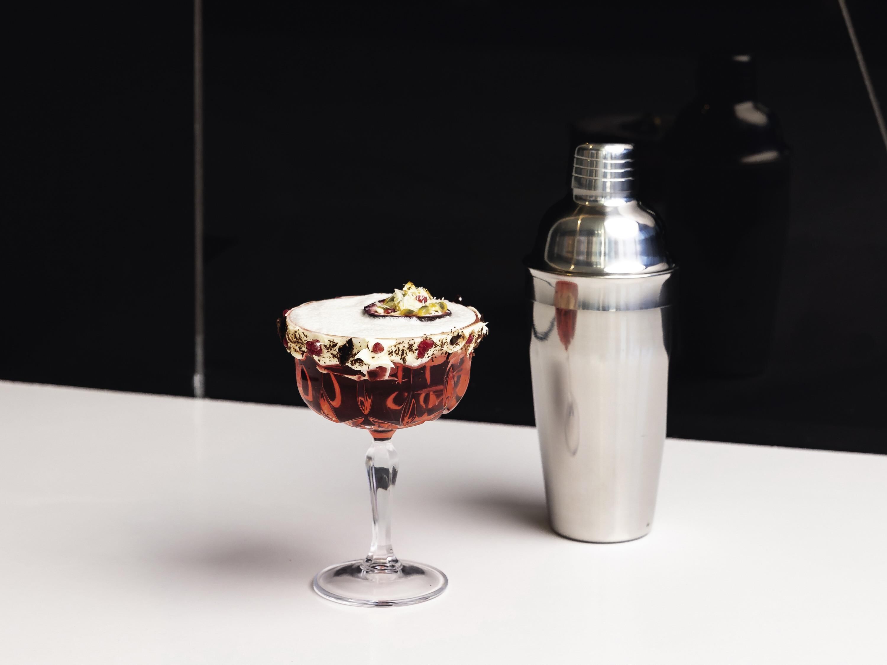 Una copa de cóctel con un borde decorativo y un shaker para cócteles a su lado.
