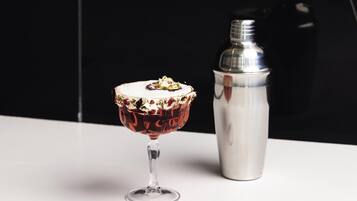 Una copa de cóctel con un borde decorativo y un shaker para cócteles a su lado.