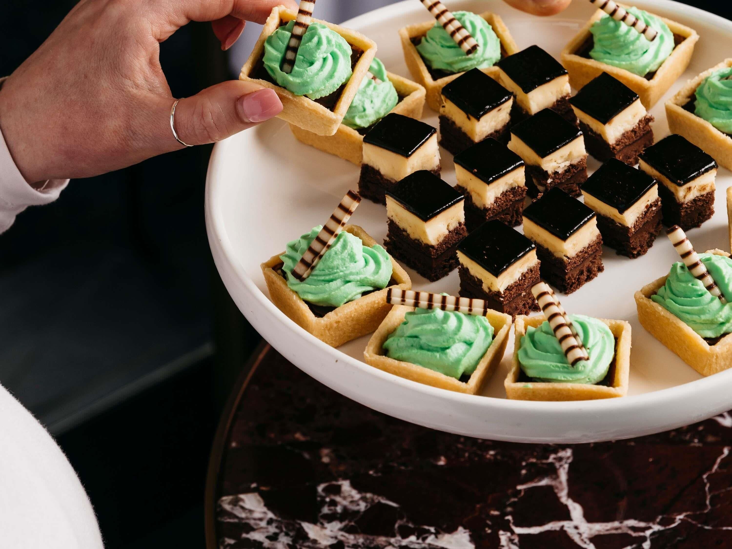 Un plato de postres con glaseado verde y cuadrados de chocolate.