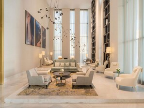 A spacious living area with a sofa, armchairs, a coffee table, and a bookshelf.