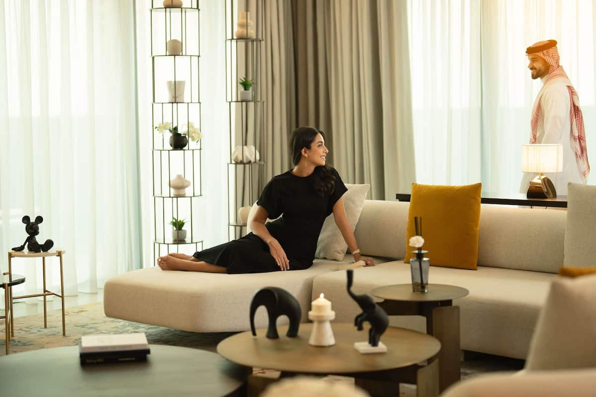 A modern living room with a sofa, a coffee table, a side table, and a decorative shelf with plants and candles.
