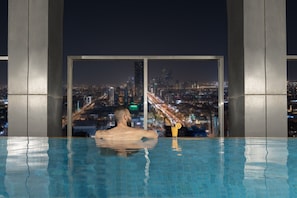 A man in a pool with a cityscape view through large windows.