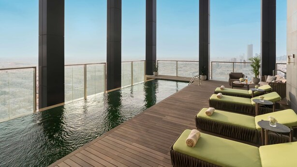 Ein Infinity-Pool auf dem Dach mit Liegestühlen und Blick auf die Stadt.