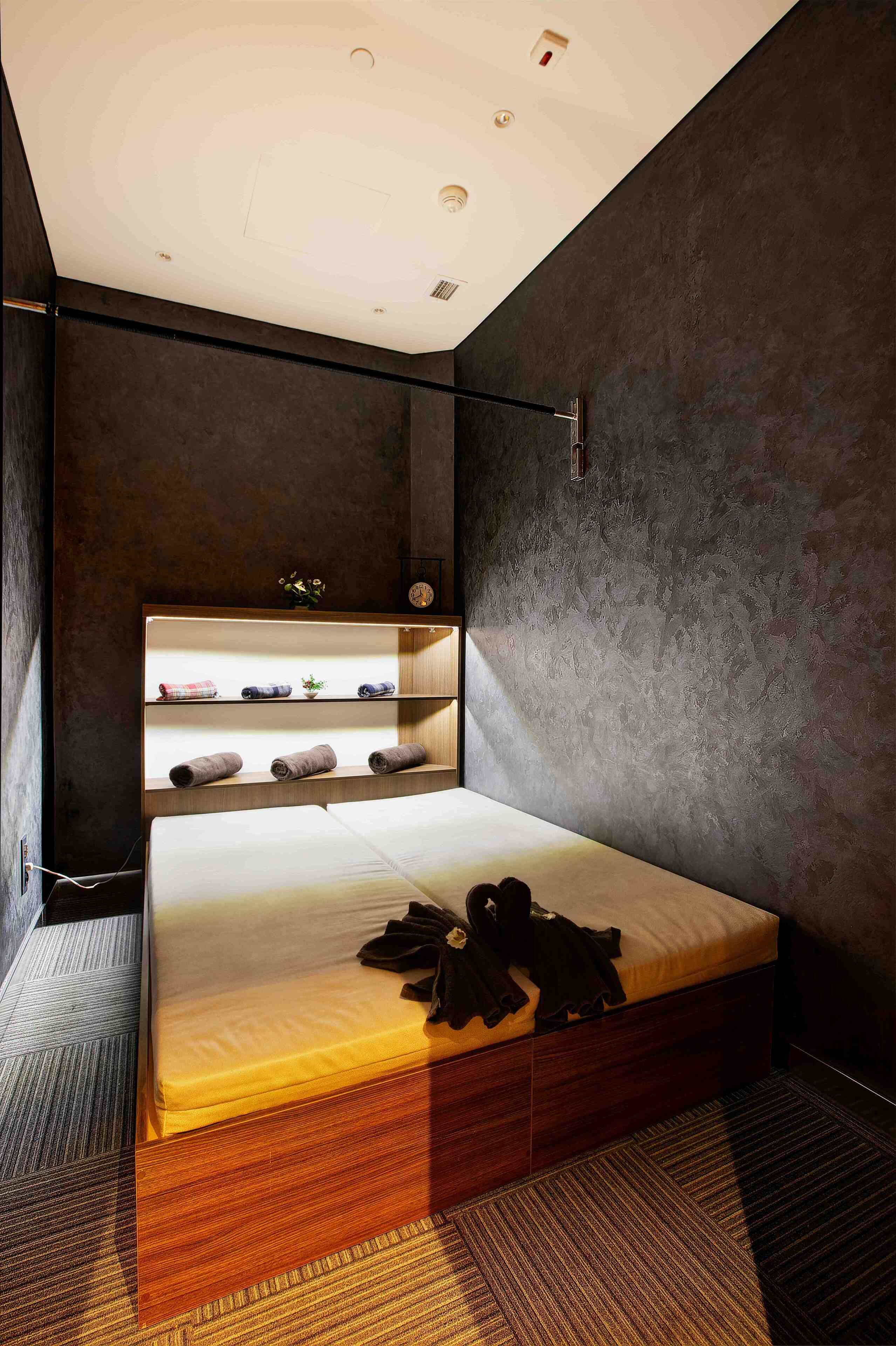 Quarto moderno com cama, estantes embutidas e relógio na parede.
