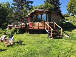 A wooden cabin with a deck and a small staircase leading to a porch.
