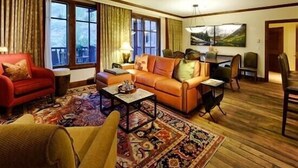 A cozy living room with a red armchair, an orange sofa, and a patterned rug. - Ritz Carlton Luxury 3 Bedroom (Aspen)