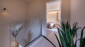Una habitación de hotel moderna con un separador de vidrio, una cama con cubrecama blanco y una mesita de noche.
