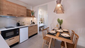 Una cocina moderna con armarios de madera, microondas integrado y un comedor con mesa y sillas de madera.