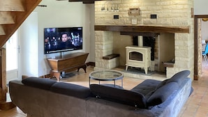 Una sala de estar acogedora con chimenea de piedra, vigas de madera, televisor de pantalla plana y un sofá cómodo.