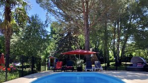 Una piscina de borde curvo, rodeada por un solárium con baldosas.