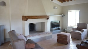 Una sala de estar con chimenea, televisión y asientos.
