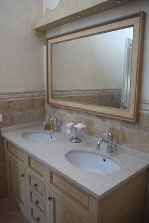 Un bagno con due lavandini, uno specchio e un mobile con cassetti.
