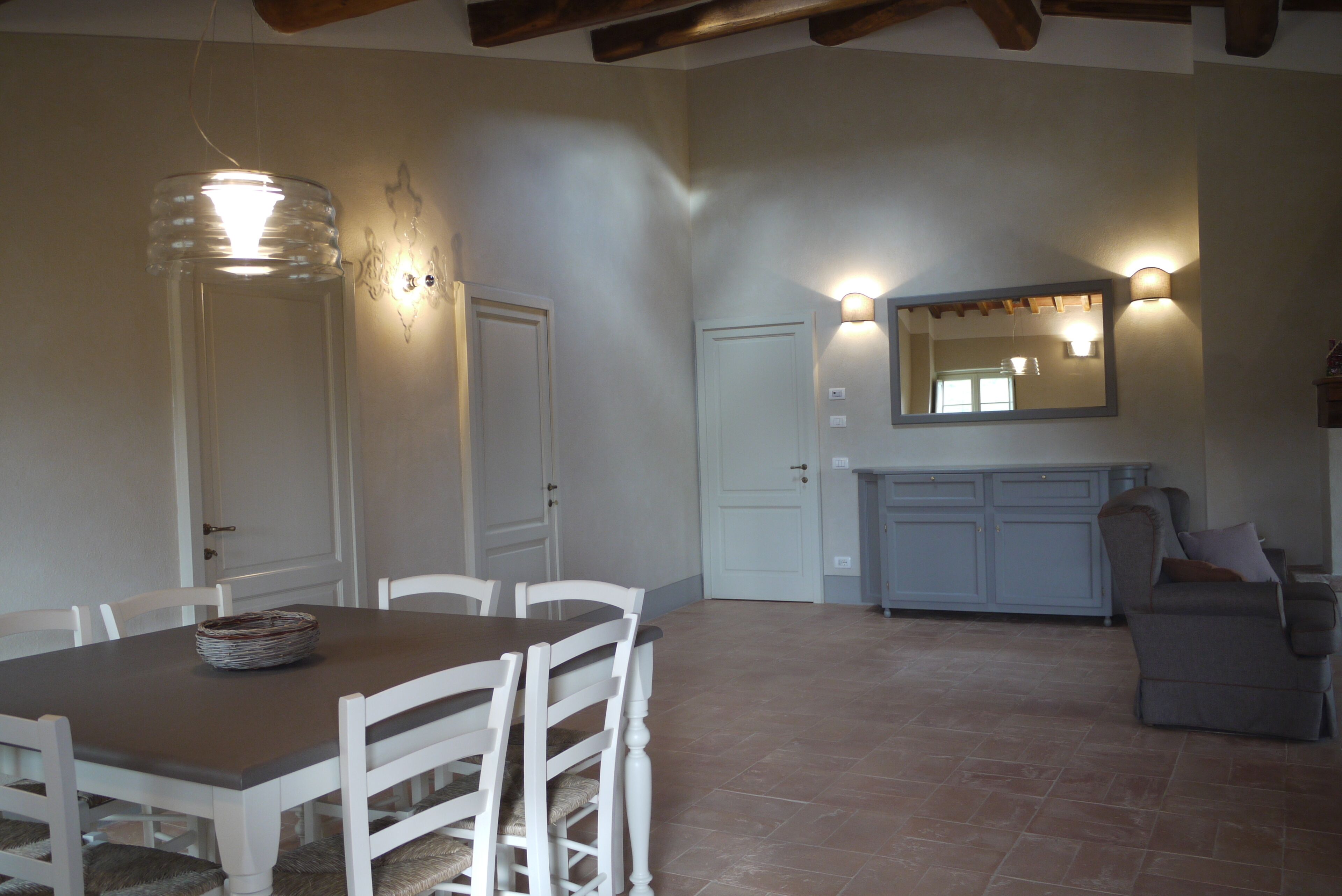 A dining area with a table and chairs, a light fixture, a cabinet, and a mirror.
