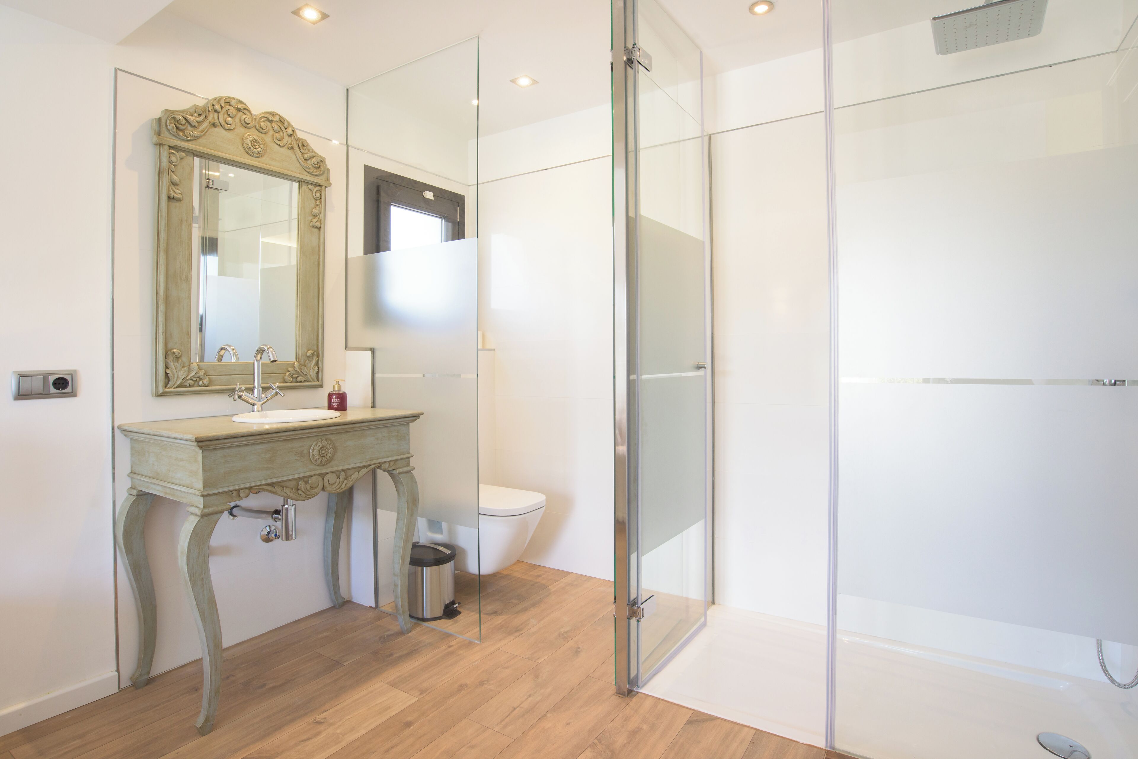 Ein modernes Badezimmer mit Waschtisch, Spiegel, Toilette und Duschkabine aus Glas.