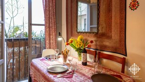 A dining area with a table set for two, a vase with flowers, and a bottle of wine. - Casa Sophia (Syracuse)