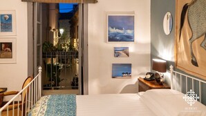 A bedroom with a bed, a nightstand with a lamp, and a wall with framed pictures. - Casa Sophia (Syracuse)