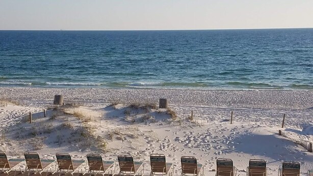 Ein Strand mit Reihen von Liegestühlen, die zum Meer ausgerichtet sind.