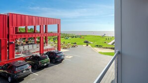 A red building with a view of a grassy area and parked cars. - 3-Bedroom, 2.5-Bathroom Suite at REAL Watersports (Waves)