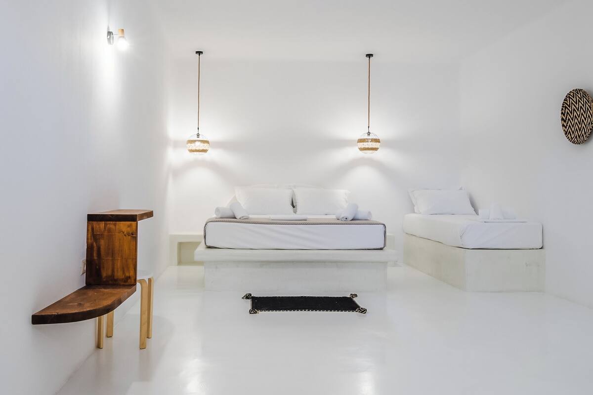 A minimalist bedroom with a bed, bedside tables, and pendant lighting.