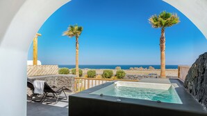 Un jacuzzi con vista despejada al océano, dos palmeras y un muro de piedra.