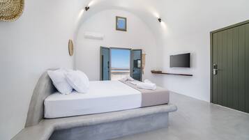 Un dormitorio moderno con cama, televisión y vista al mar.