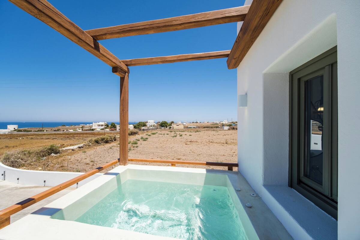 A balcony with a hot tub overlooking a beach.