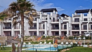 A modern hotel with multiple balconies, a swimming pool, and solar panels on the roof. - Casares Del Mar (Casares)