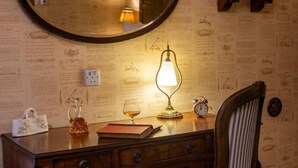 Et værelse med et træskrivebord, et spejl, en lampe, en stol og en væg med dekorative mønstre.