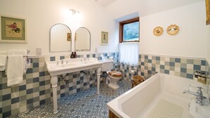 Et badeværelse med gulv i skakmønster, en hvid vask, toilet og badekar.
