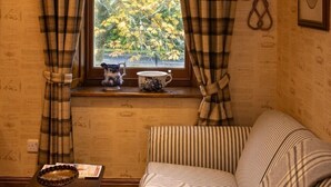 Et hyggeligt værelse med et vindue, en stribet sofa og et bord med en kande og en skål.