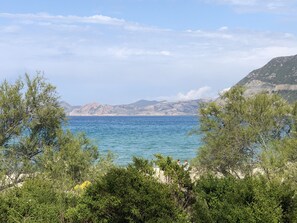 Un paisaje costero con mar azul cristalino, montañas rocosas y vegetación verde exuberante.