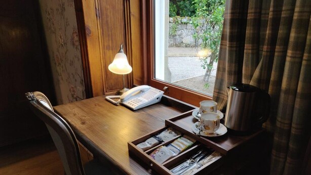 A wooden table with a telephone, a tray with cups and saucers, and a box of tissues. - Rhododendron Suite -With views of the rhododendron trees on the hillside (Inverness)