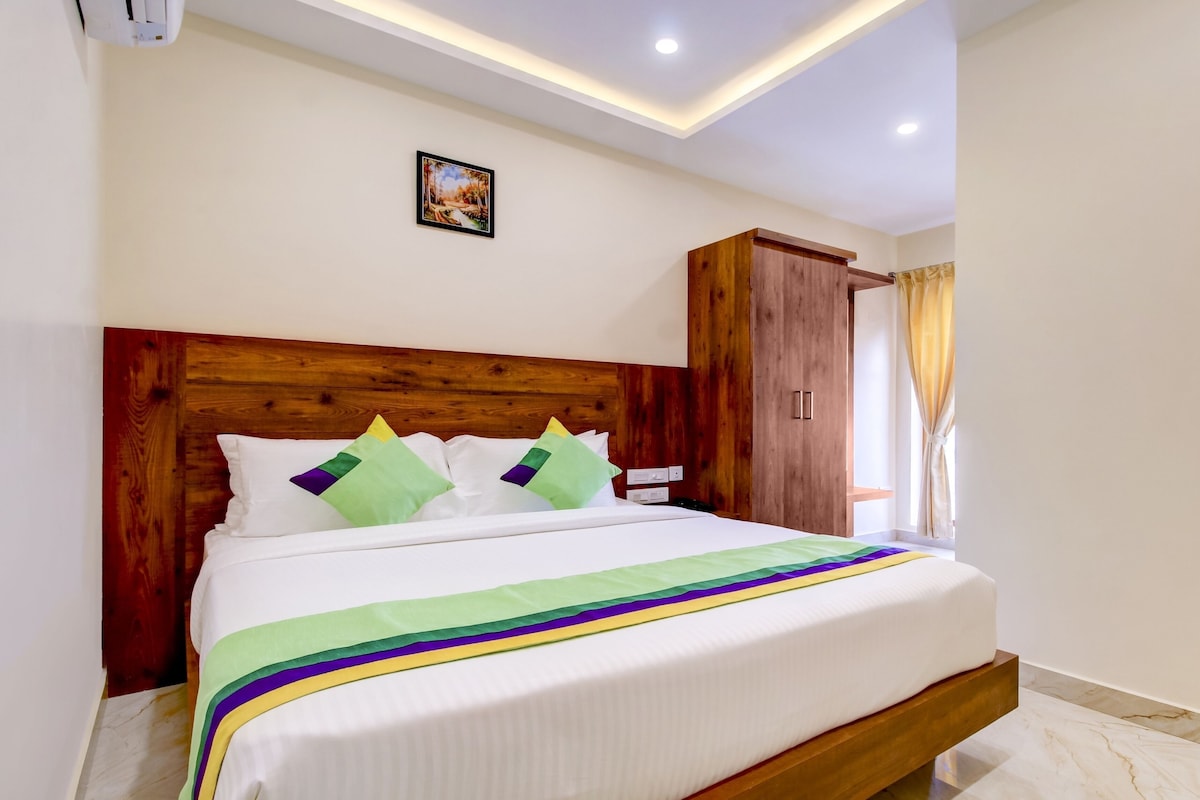 Una cama bien hecha con cabecera de madera, un cuadro pequeño en la pared y un armario con cortina.