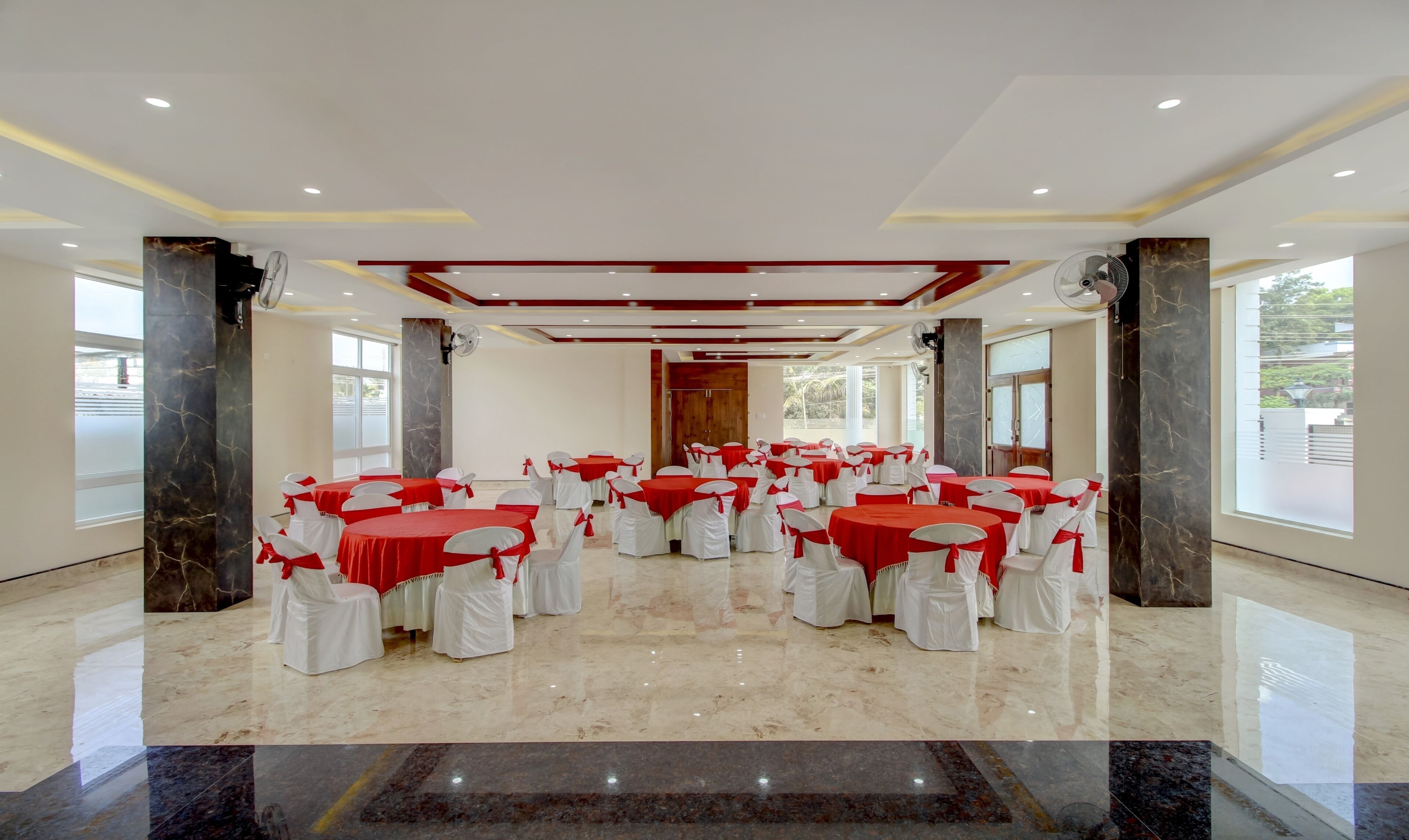 A conference room with multiple tables and chairs, marble flooring, and large windows.