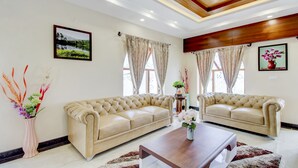 Un salón amplio con dos sofás color beige, una mesa de centro de madera y jarrones decorativos.