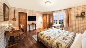 A cozy bedroom with a bed, a desk with a lamp, a chair, a window with curtains, and a wooden door. - The wooden floors, vintage furniture, and tartan accents create a comfy room (Inverness)