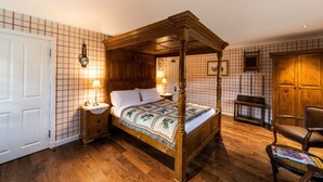A four-poster bed with a wooden frame, a bedside table with a lamp, and a bench in a room with wooden flooring and plaid wallpaper. - The wooden floors, vintage furniture, and tartan accents create a comfy room (Inverness)