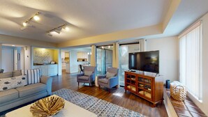 A spacious living room with a sofa, two armchairs, a coffee table, and a TV on a wooden cabinet. - Large Golf Course Villa with Lots of Space for Everyone! (Hilton Head)