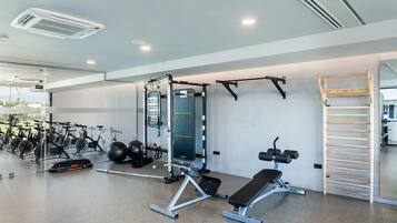 A modern gym with exercise equipment, a bench, and a wall-mounted rack.
