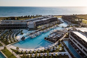 Ein Resort mit einem großen zentralen Pool, mehreren Gästezimmern und Blick auf den Ozean.