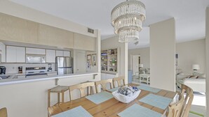 Uma cozinha moderna com armários brancos, uma ilha central e um lustre.
