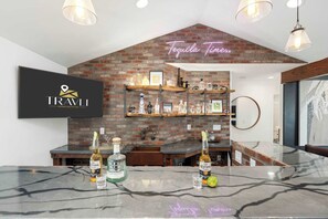 A bar area with a brick wall, shelves with liquor bottles, and a neon sign reading "Tequila Time."